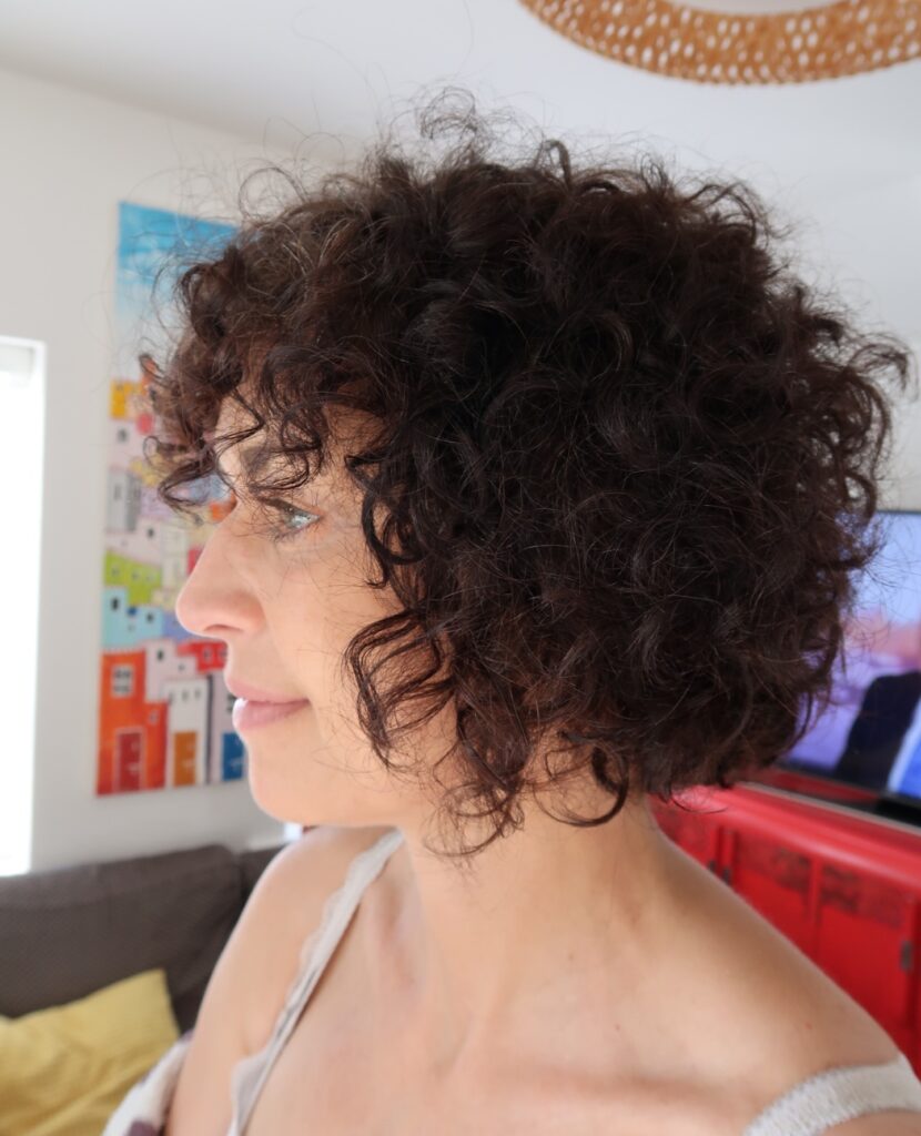 Short brunette curly bob with tousled texture and soft rounded layers.