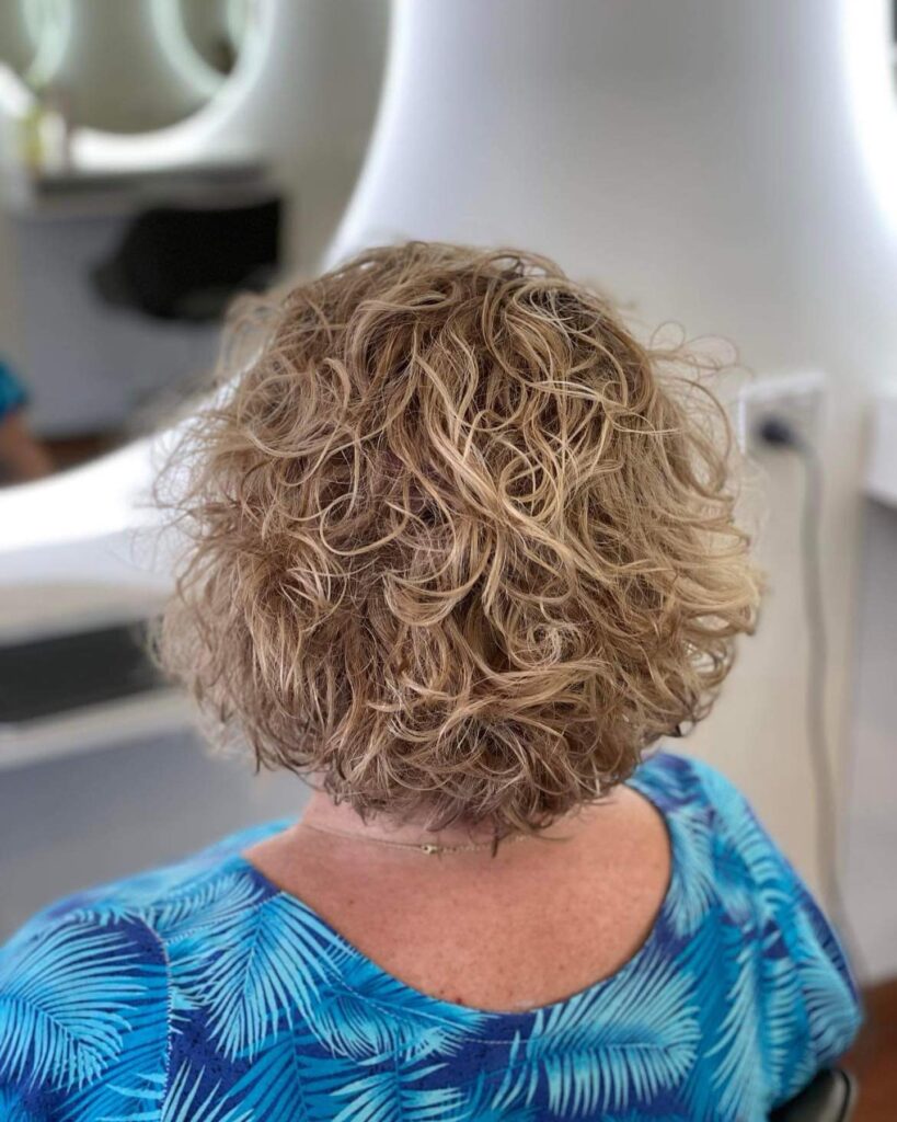 Tousled blonde curly bob with soft layers and rounded volume.