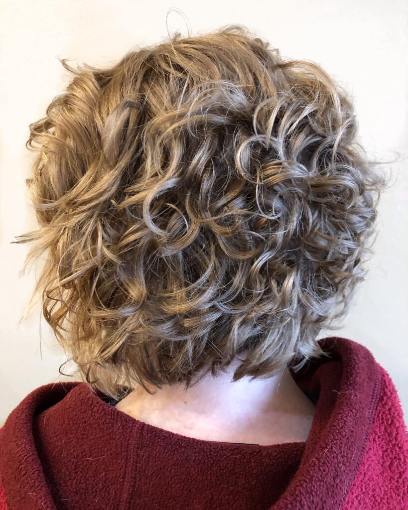 Honey blonde layered curly bob with soft spiral curls and rounded volume.