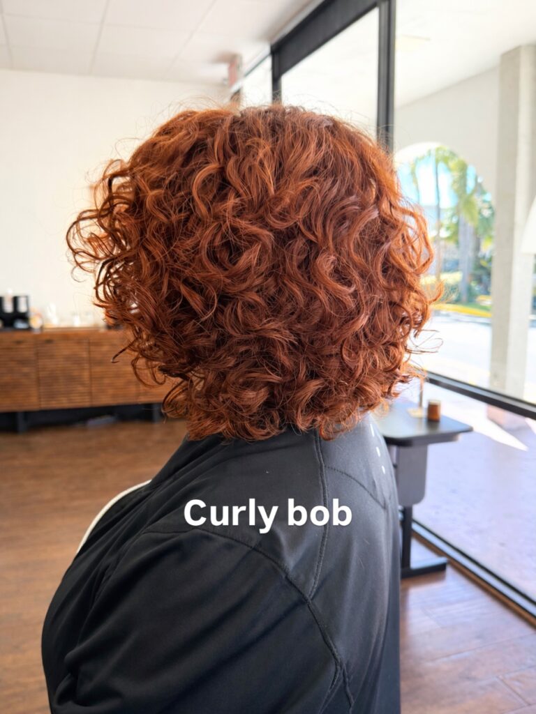 Bright copper curly bob with rounded layers and defined bouncy curls.
