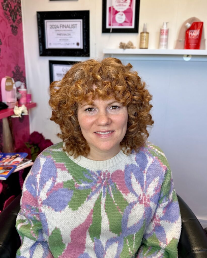 A rounded ginger curly bob with tight ringlets and a curly fringe.