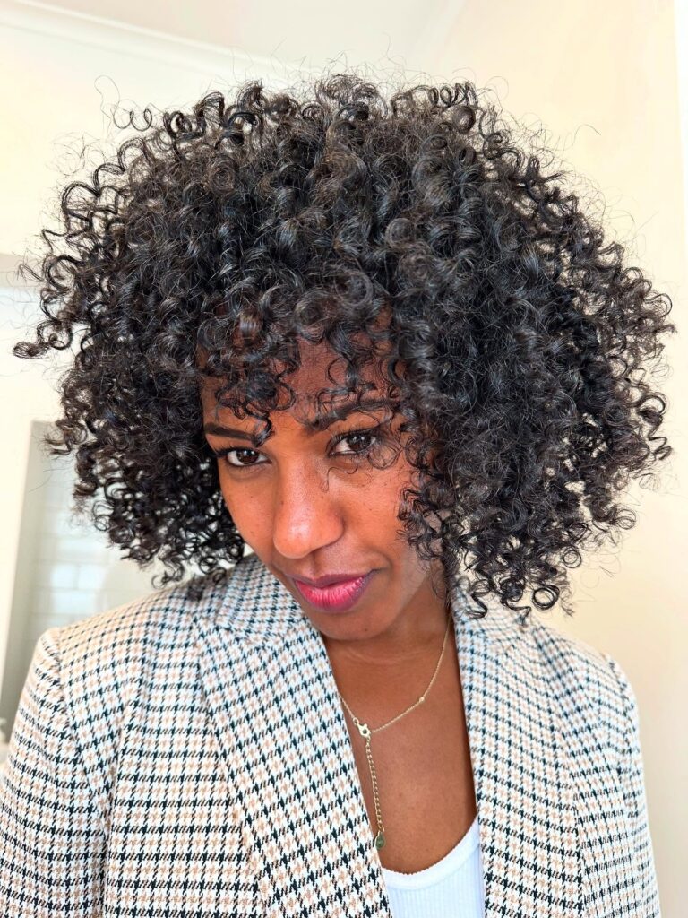 Defined spiral curly bob with rounded layers and soft curly bangs.