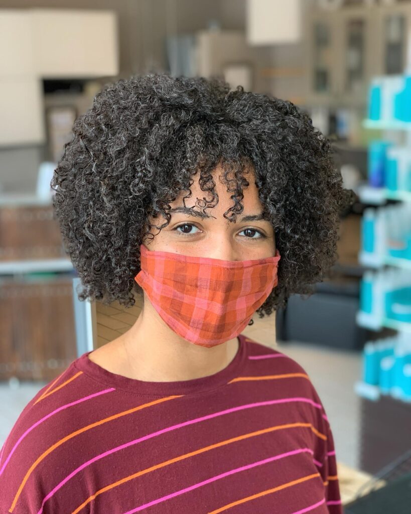 A rounded natural curly bob with dense dark curls and layered volume.