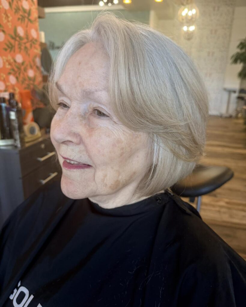 Soft silver layered bob with curtain bangs and smooth rounded ends.