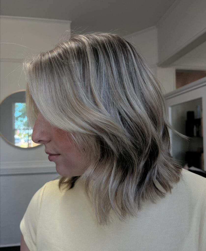 Cool blonde layered bob with soft waves and long curtain bangs.