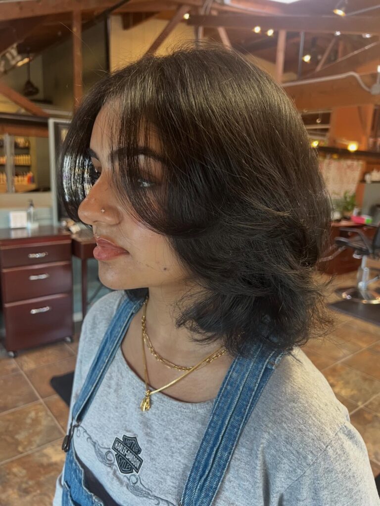 Glossy black layered bob with feathered curtain bangs and flipped ends.