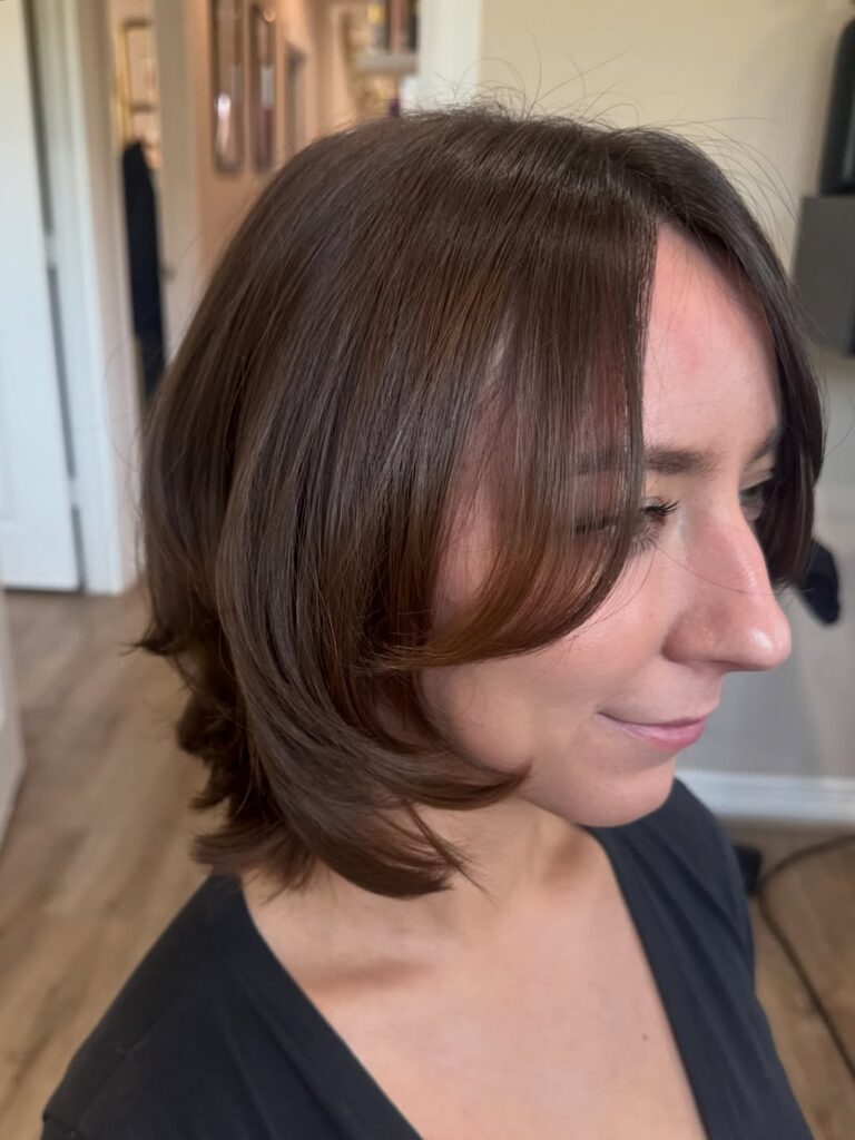 Chestnut brown layered bob with curtain bangs and curved face-framing layers.