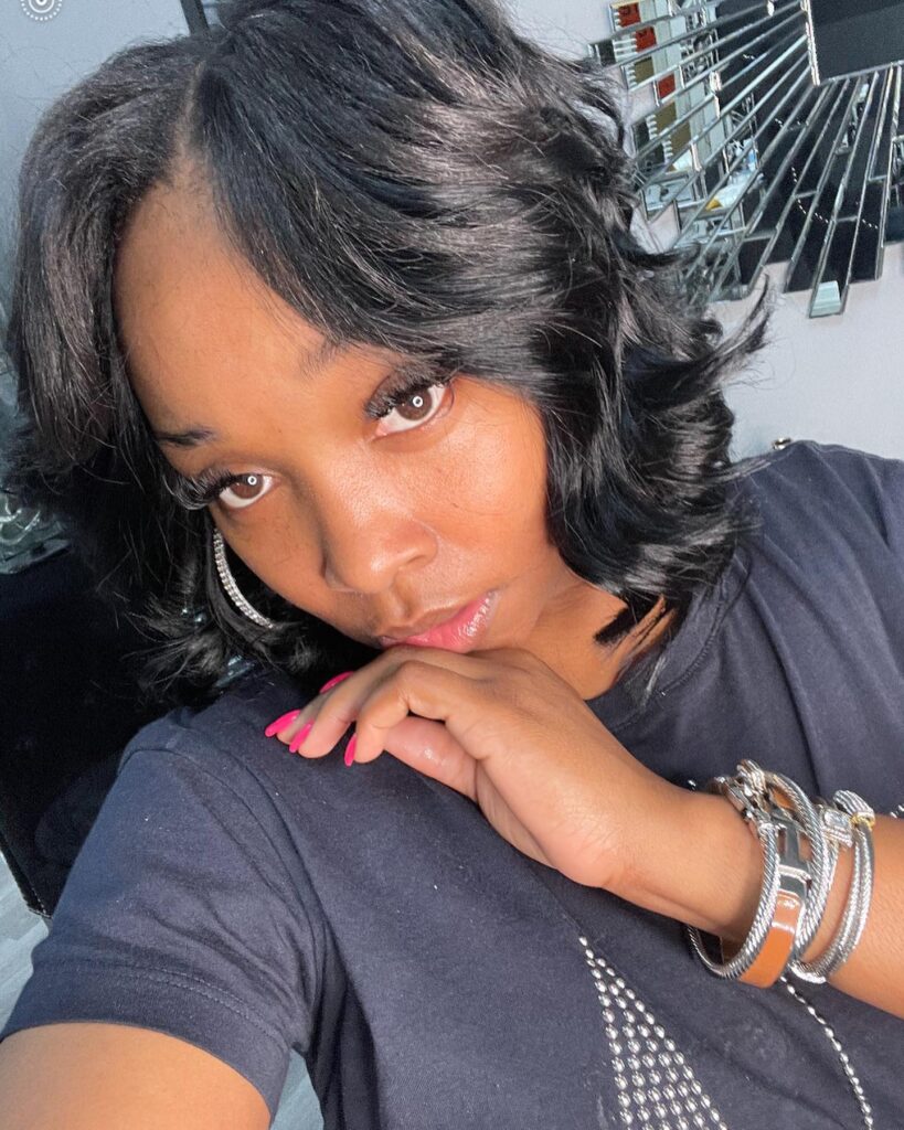 Glossy black layered bob with voluminous curtain bangs and curled ends.