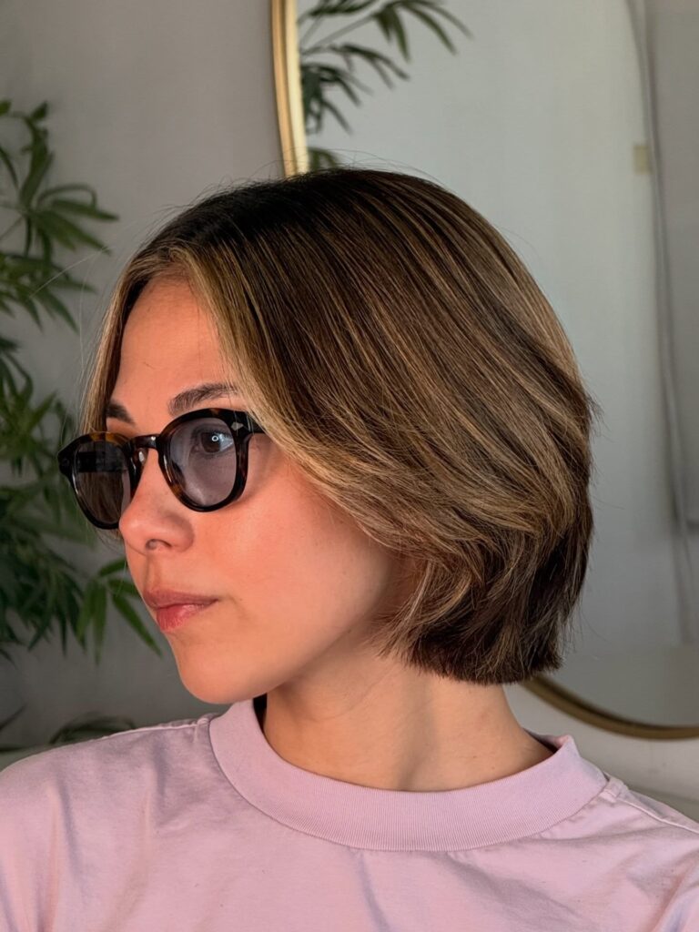 Smooth brunette layered bob with beige highlights and soft curtain bangs.