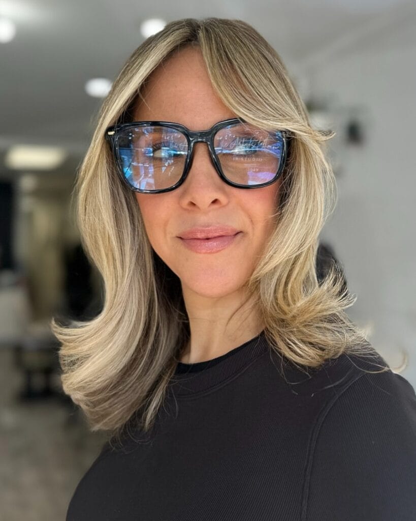 A woman with a medium-length champagne-blonde lob featuring flicked-out layers and a soft curtain fringe.