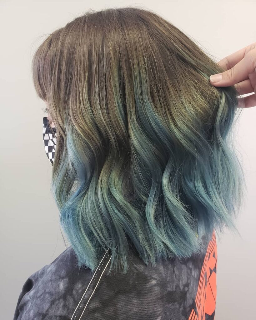 A woman with shoulder-length brown hair featuring a seamless transition into vibrant blue balayage at the ends.