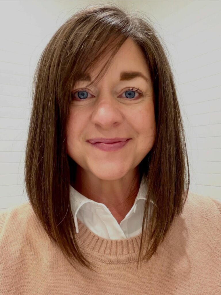 A woman with a sleek shoulder-length dark brown lob and wispy side-swept bangs.