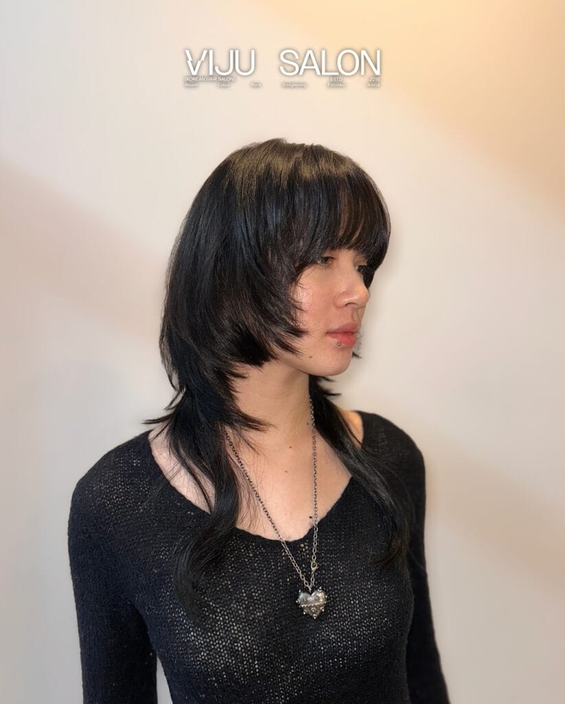 A person with straight black hair featuring a disconnected layered shag with a thick fringe and longer wispy ends.
