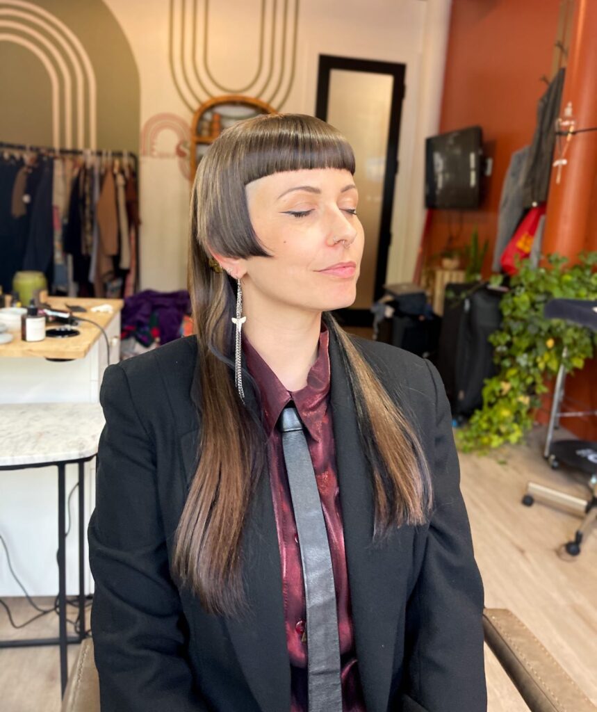 A woman with long, straight, dark hair in a hime cut with thick blunt bangs and curved side layers.