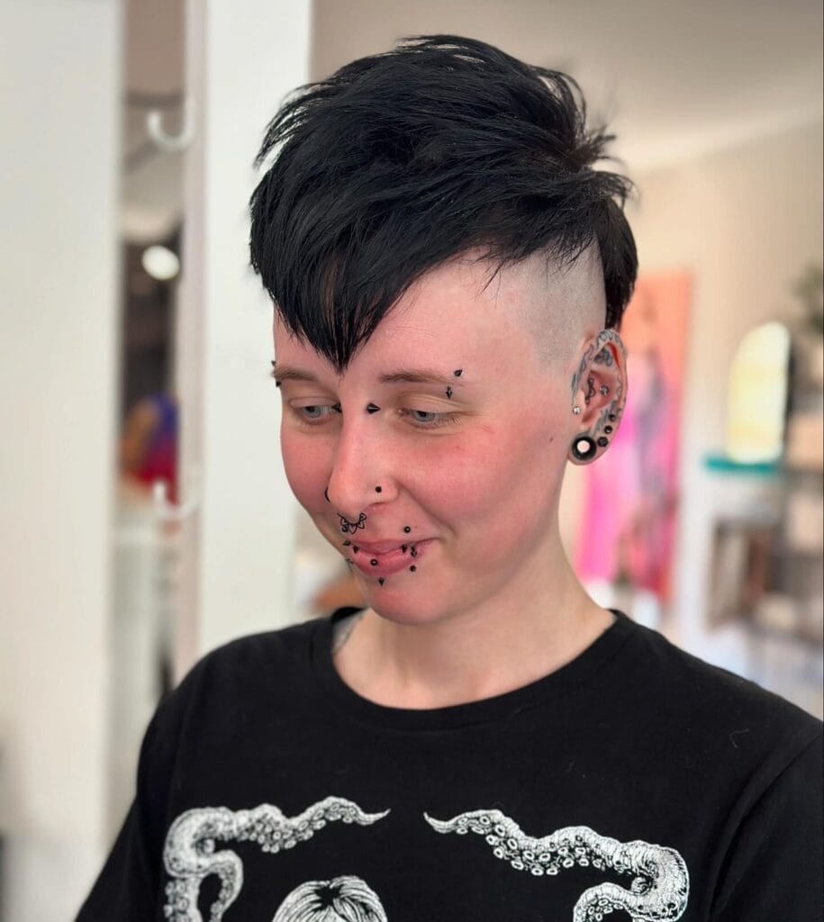 A person with a spiky jet-black pixie cut featuring high shaved sides and a pointed fringe.