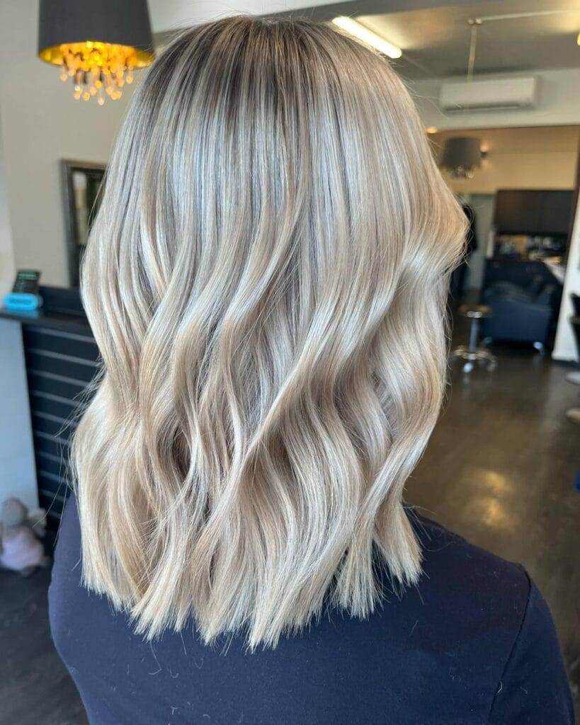 Collarbone-length blonde lob with soft textured ends and loose, natural waves that add movement and dimension.