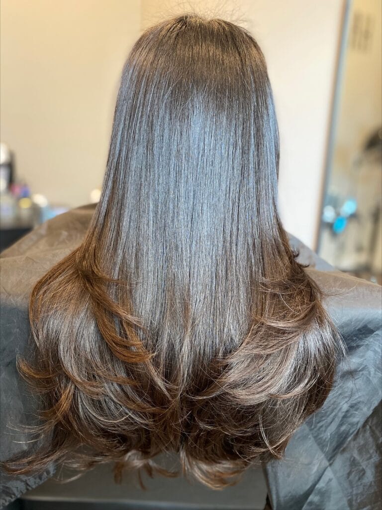 Long, smooth brunette hair with soft long layers and gently flipped ends that create natural movement and volume at the bottom.