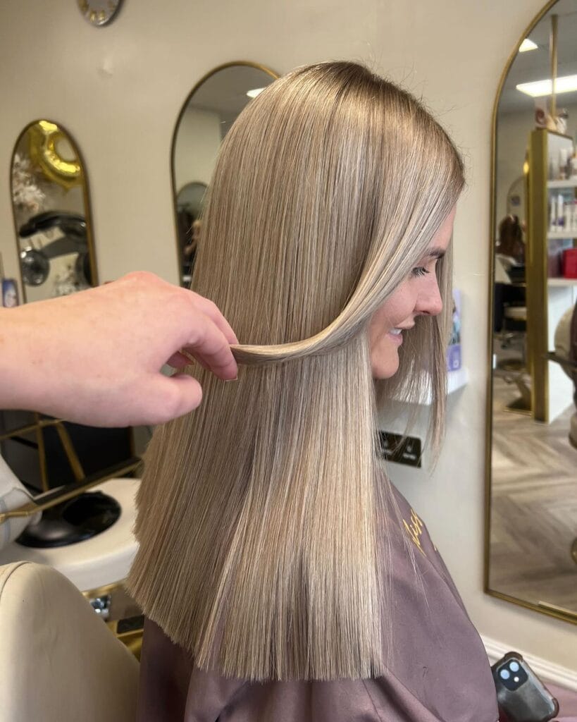 Sleek shoulder-length blonde hair with a smooth straight finish, subtle root volume, soft face-framing front pieces, and clean blunt ends for a polished, modern look.
