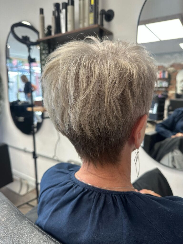 Short silver pixie cut with textured layers on top and a softly tapered nape for a light, airy shape.