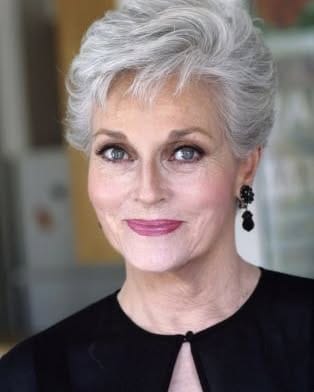 Short textured pixie cut in soft silver hair, styled with light volume and wispy layers that create a polished, elegant look.