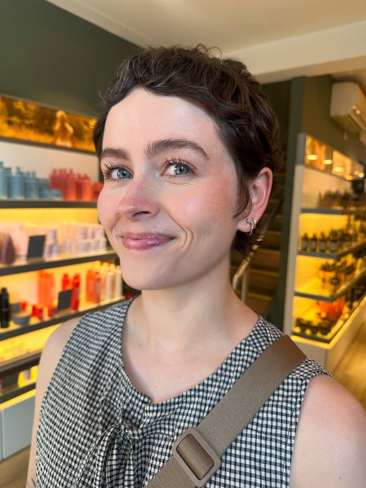 Short textured pixie haircut with soft layers and a slightly side-swept fringe, creating a natural, modern style with light volume and movement.