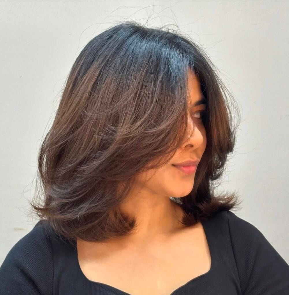 Shoulder-length layered lob with voluminous feathered layers and curtain bangs that softly frame the face.
