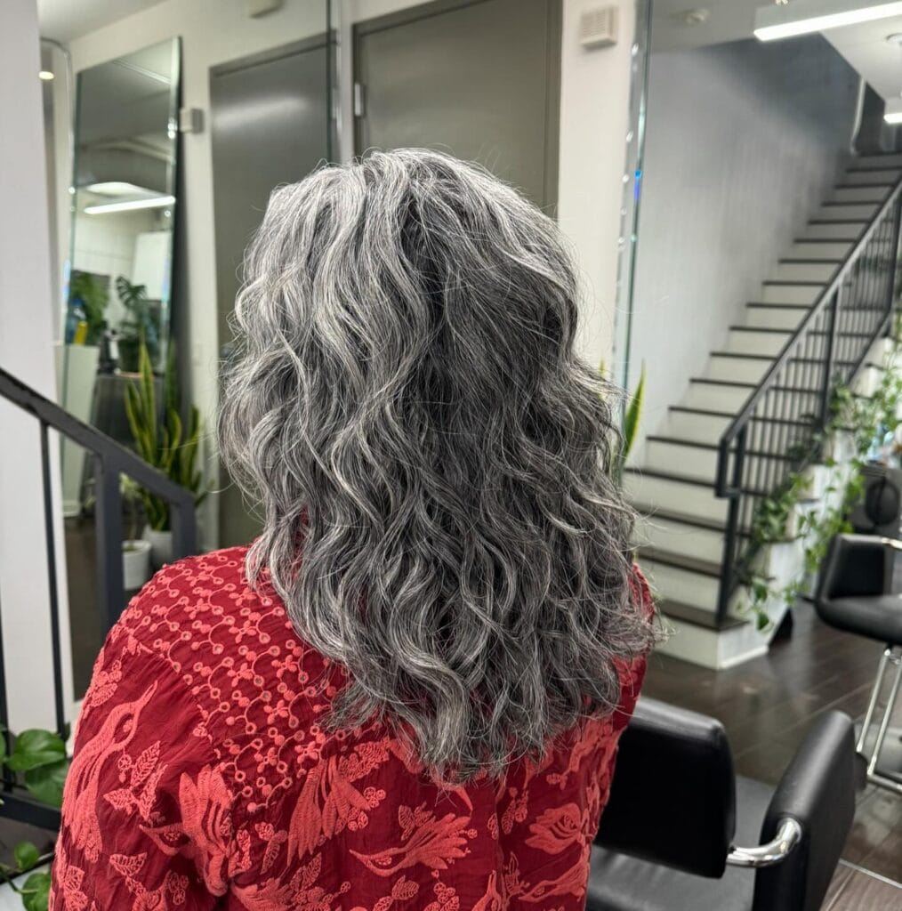 Shoulder-length wavy gray shag with textured layers and soft movement, showing a natural salt-and-pepper blend.