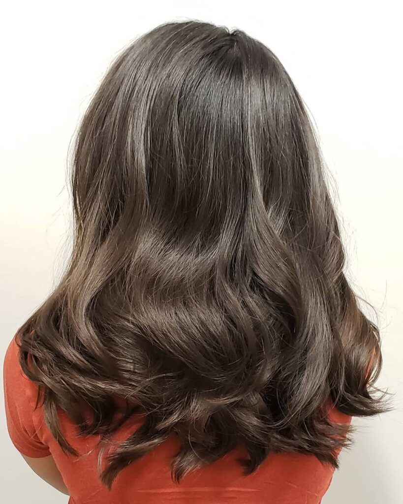 Medium to long thick brunette wavy hair with soft waves and full rounded ends.