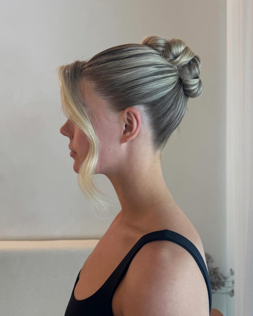 Sleek blonde low bun with a smooth finish and soft face framing strands.