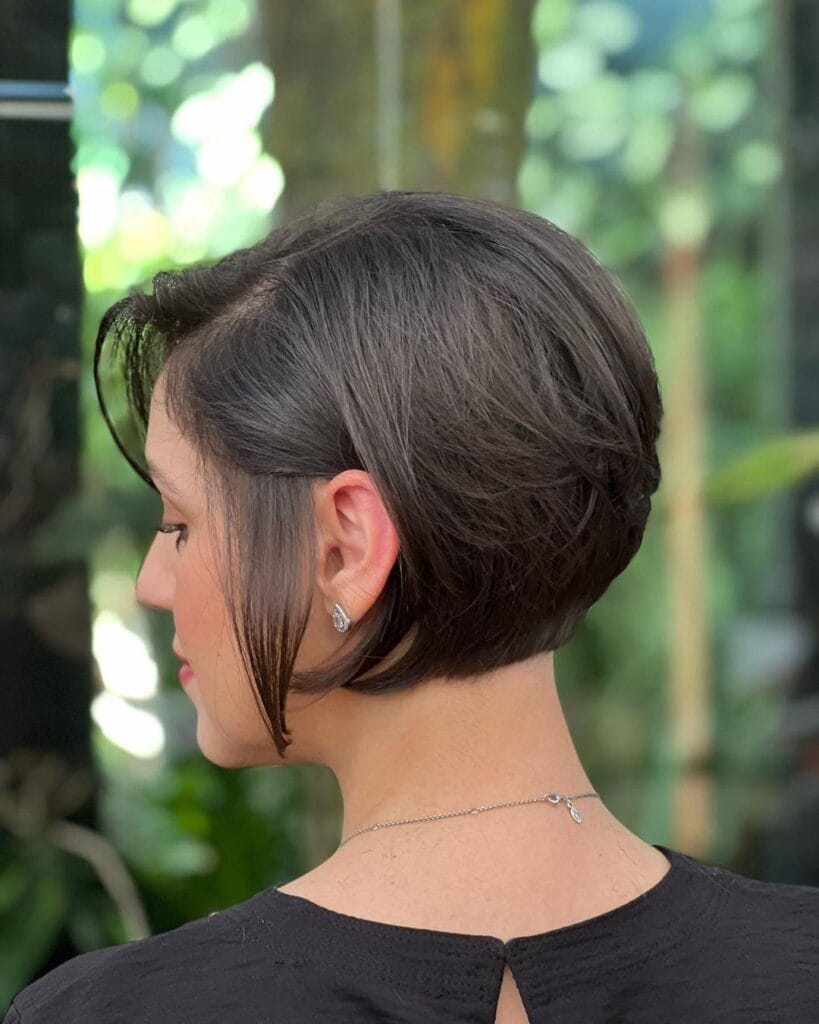 A woman with a sleek dark brunette stacked bob shows off the tapered back and side profile.