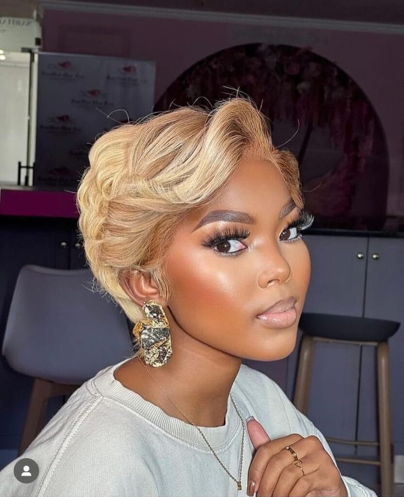A woman with short bright blonde hair styled in polished finger waves looks over her shoulder.