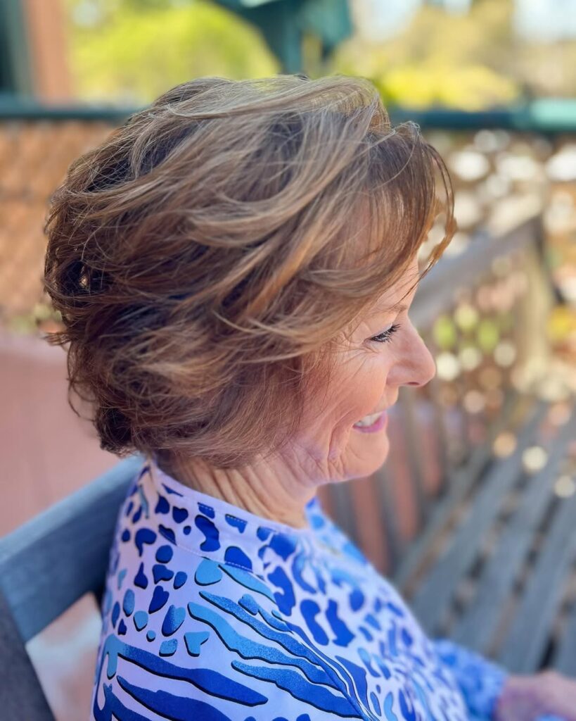 Short layered bob with volume and a soft side fringe in blended brown tones.