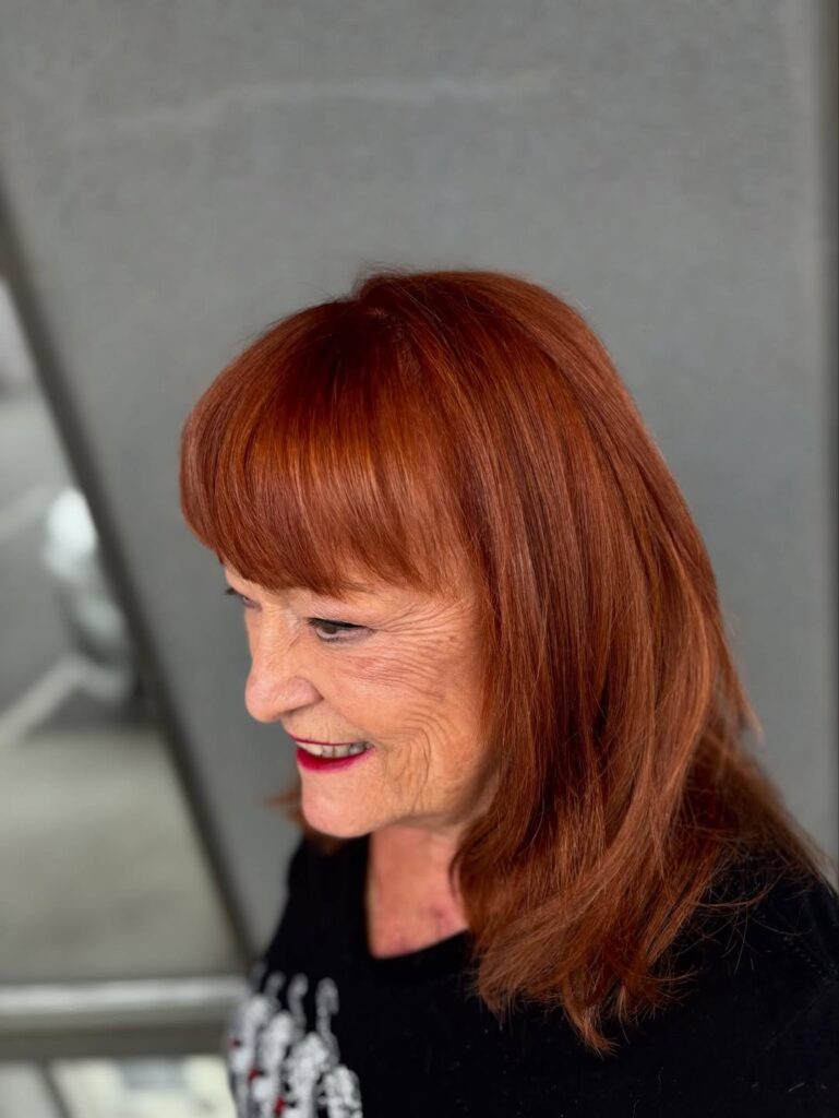 Straight copper hair with full blunt bangs and a smooth polished finish.
