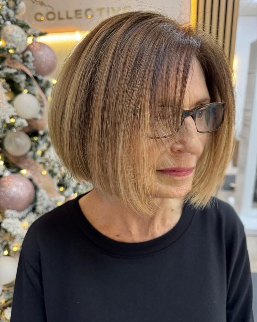 Chin-length bob with smooth layers and soft side swept bangs in warm brown tones.