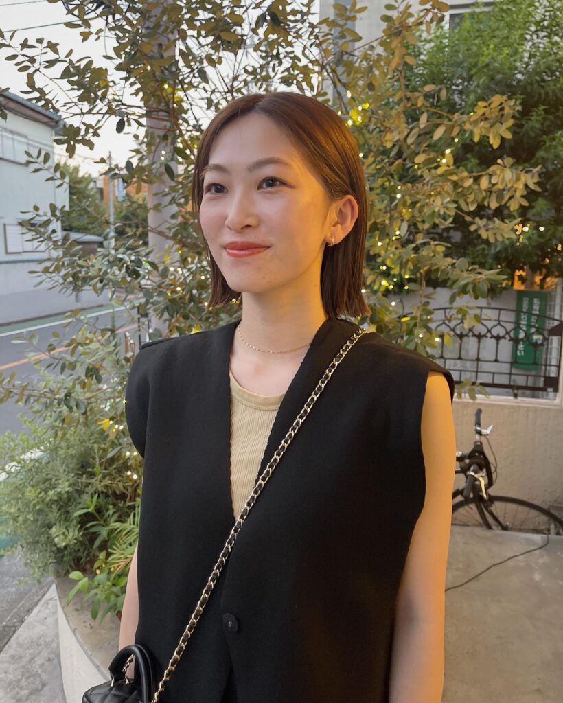 A woman with a smooth warm chestnut brunette bob styled straight and tucked behind both ears.