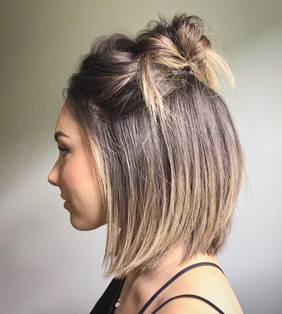 A woman in profile shows her short bob with blonde highlights styled in a half-up messy bun.