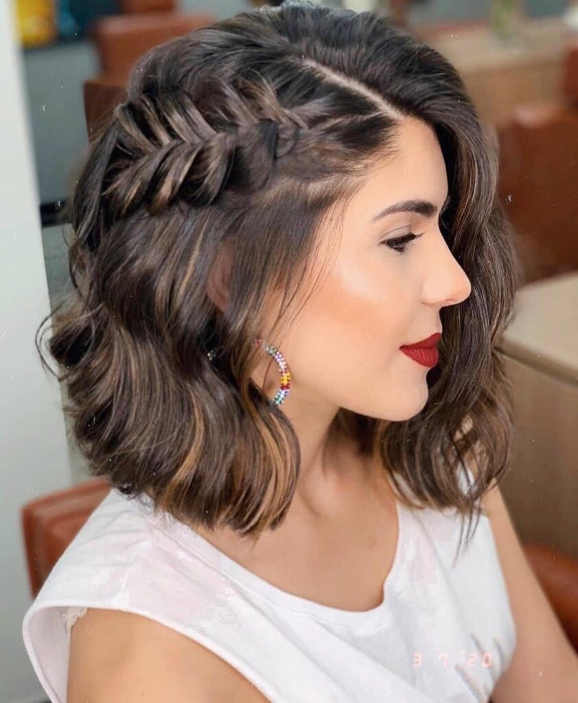 A woman with a wavy chestnut brown bob features a thick Dutch braid along the side of her head.