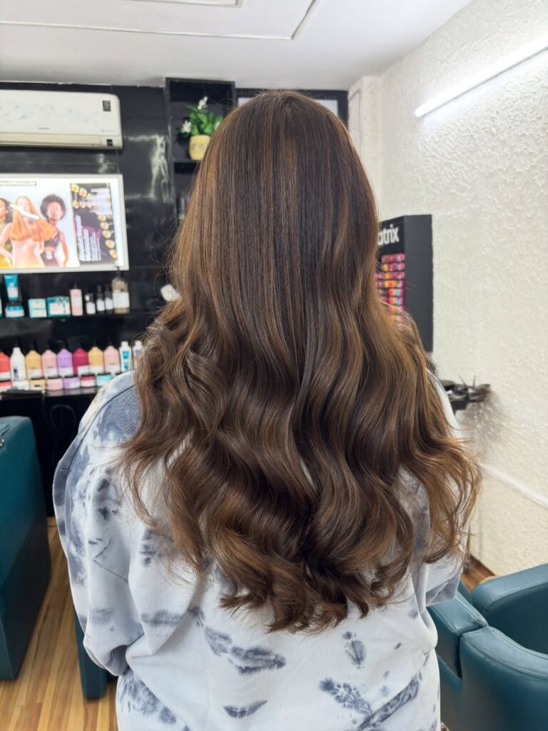 Long brunette hair with defined glossy waves and layered shape.