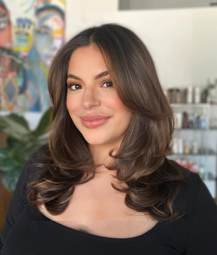 Medium length layered hair with soft volume and blended bangs framing the face.
