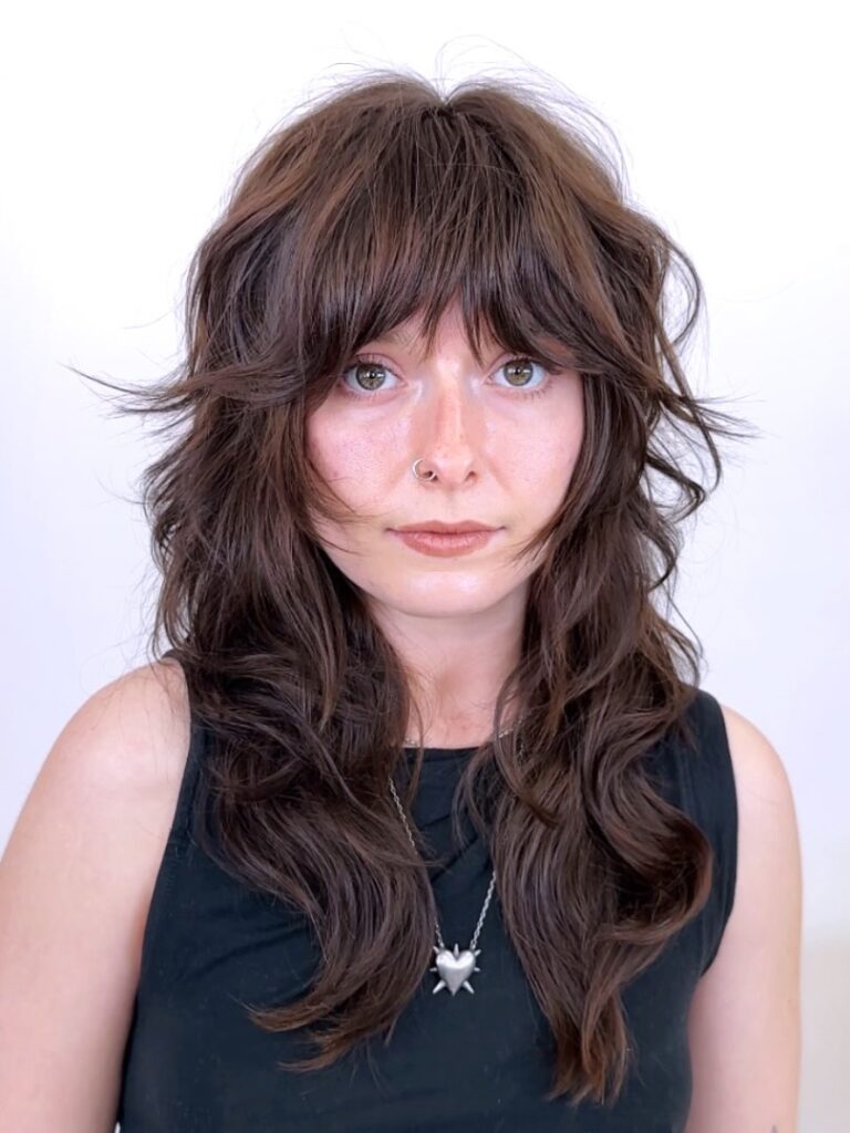 Medium length shaggy layered hair with tousled bangs and natural textured movement. 