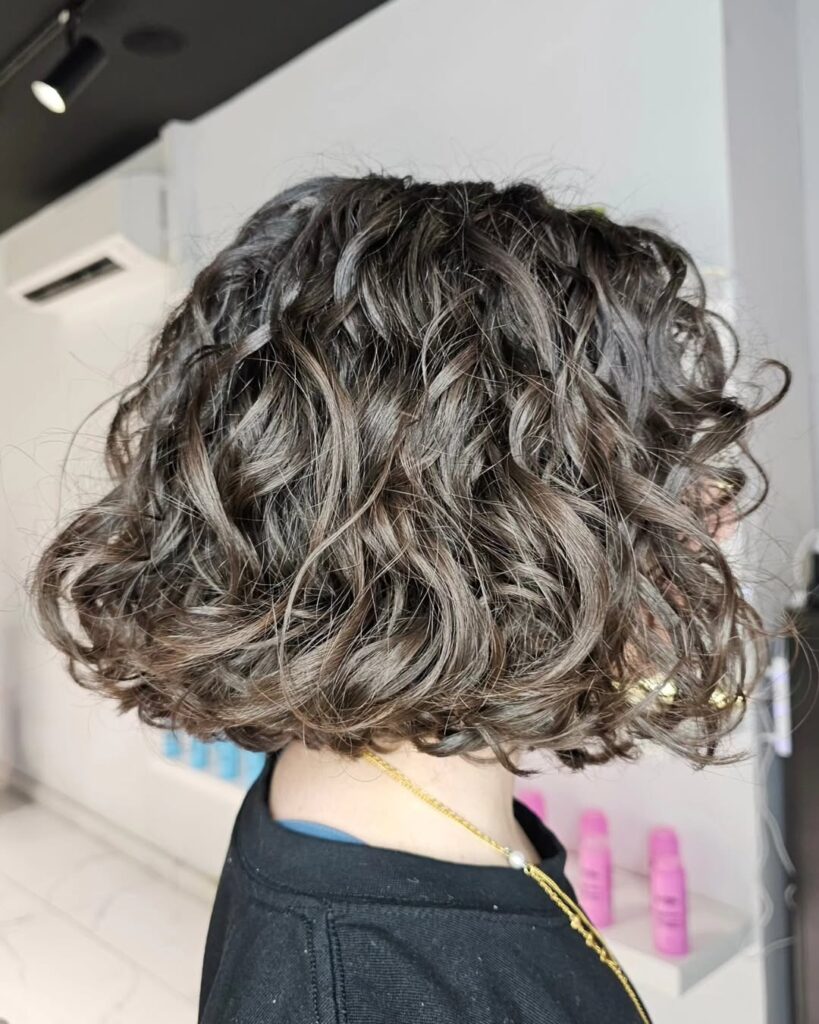 A woman with a gray wavy bob featuring layered texture and soft volume.