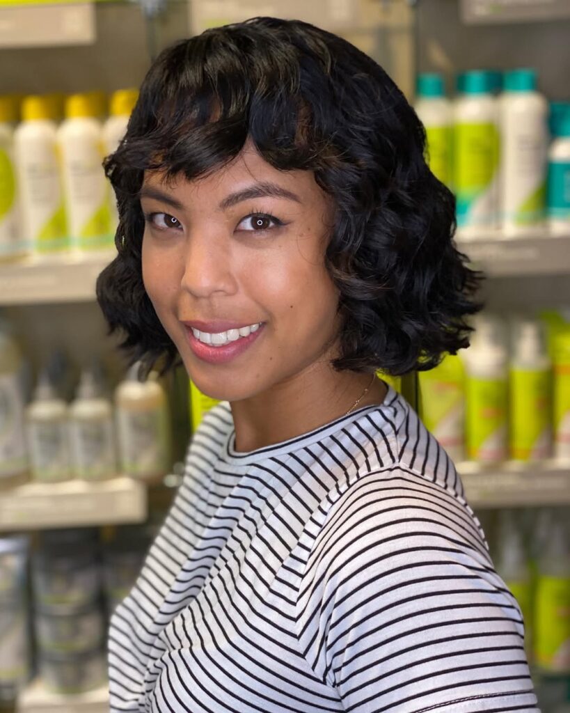 A woman with a short curly wavy bob with defined texture and volume.