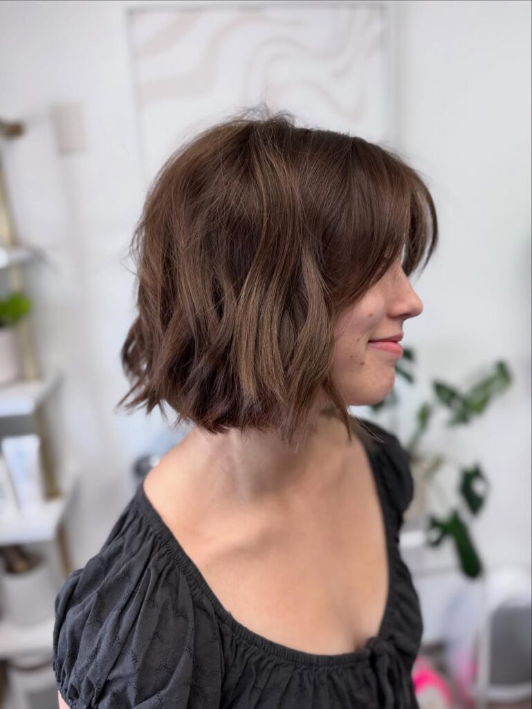 A woman with a short brunette wavy bob with soft layers and rounded waves.