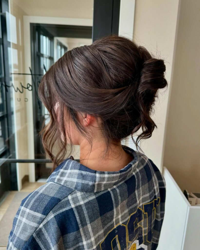 Brown hair in a relaxed messy bun secured with a clip and loose strands around the face.