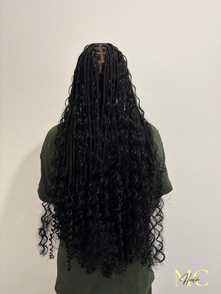 A back view of a person with long black knotless braids mixed with voluminous wavy curls reaching the lower back.