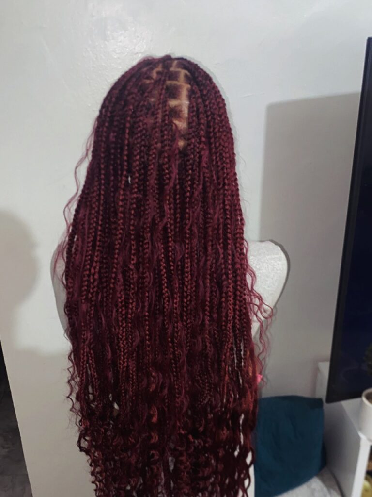 A back view of long burgundy red knotless braids mixed with wavy loose hair strands for a goddess braid effect.