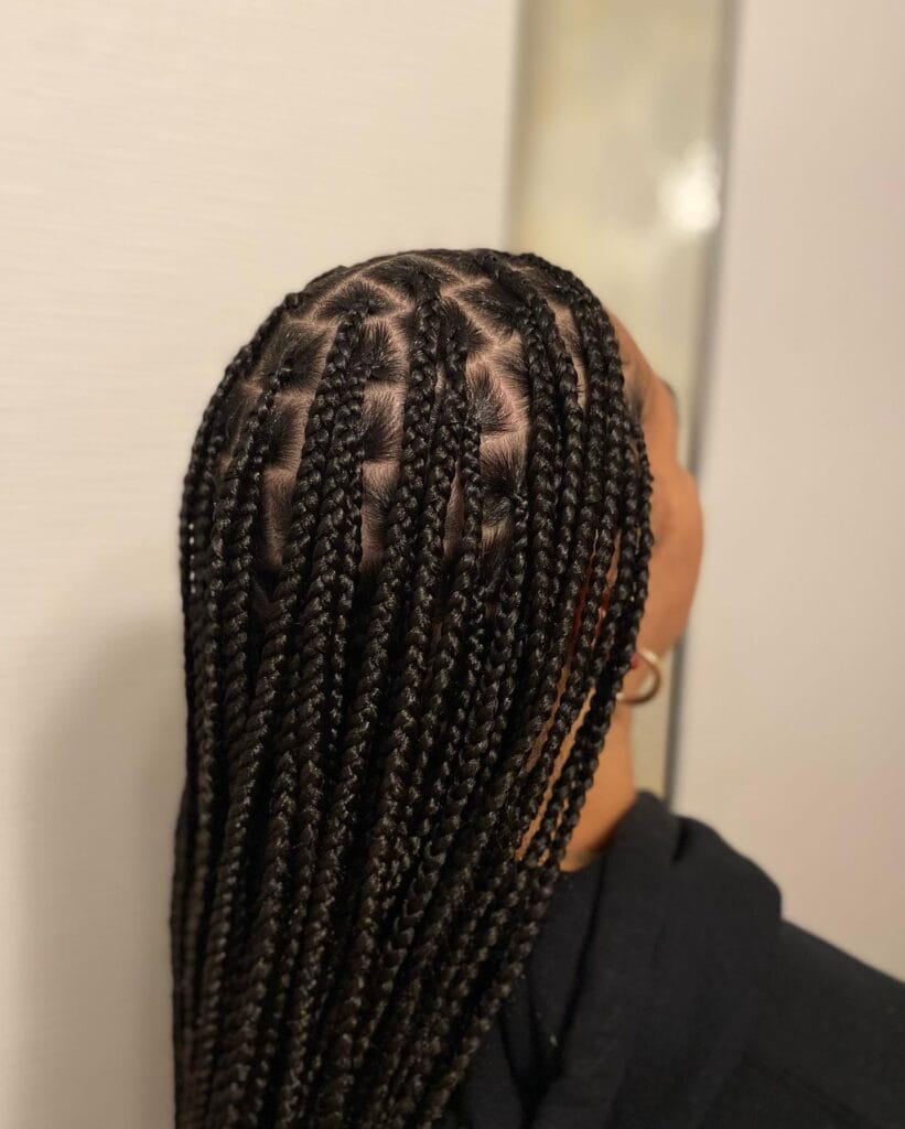 A top down view of a person with long black box braids showing off very neat and precise square partings on the scalp.