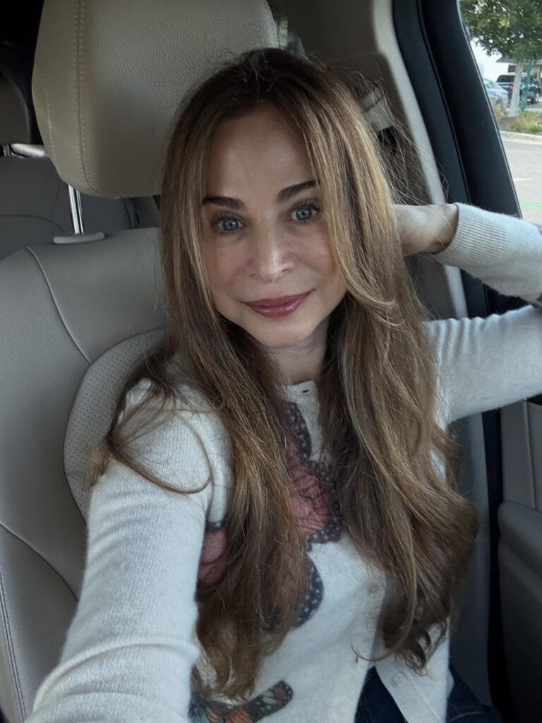 A woman with long brunette hair featuring caramel highlights and soft flowing layers throughout.