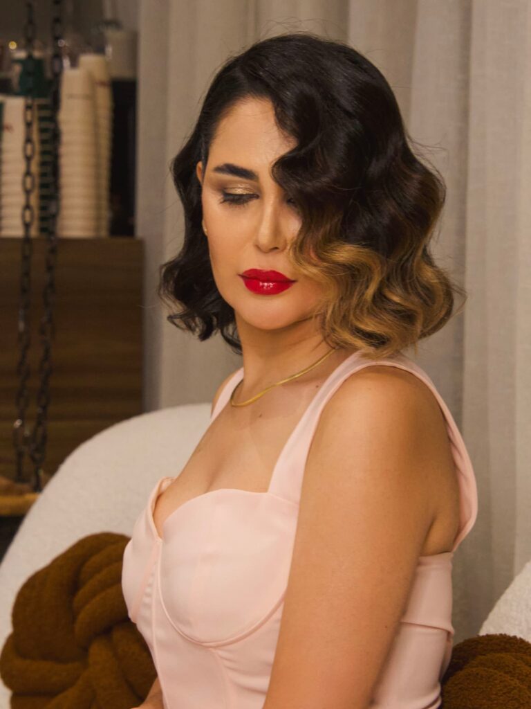 A woman with a dark brunette and honey blonde ombre bob styled in voluminous, glossy Hollywood waves.