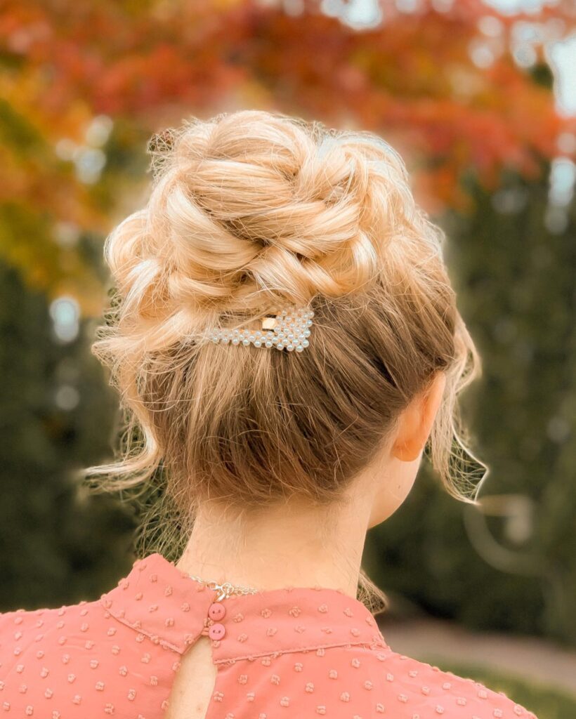 A high blonde updo made of thick braids and accented with a small pearl hairpin.